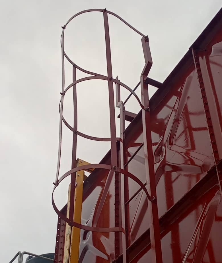 Caged access ladder on a red pressed steel tank