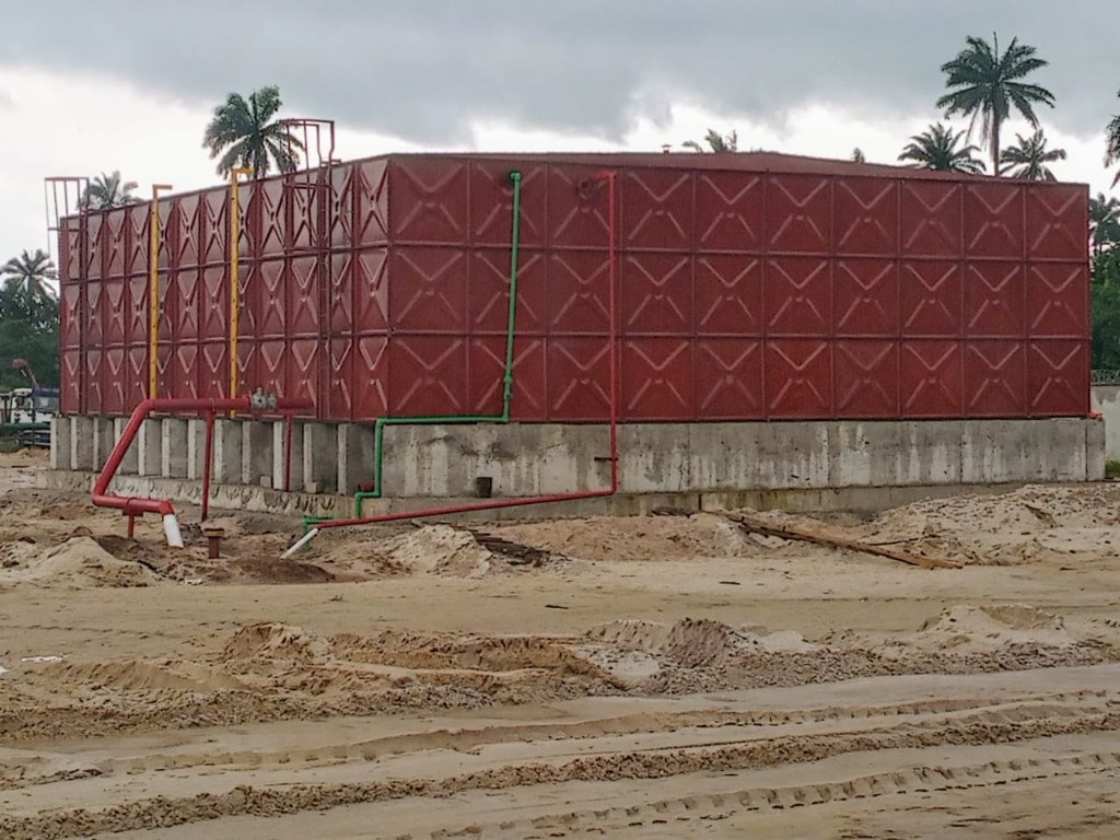 Red pressed steel water tank on a concrete base